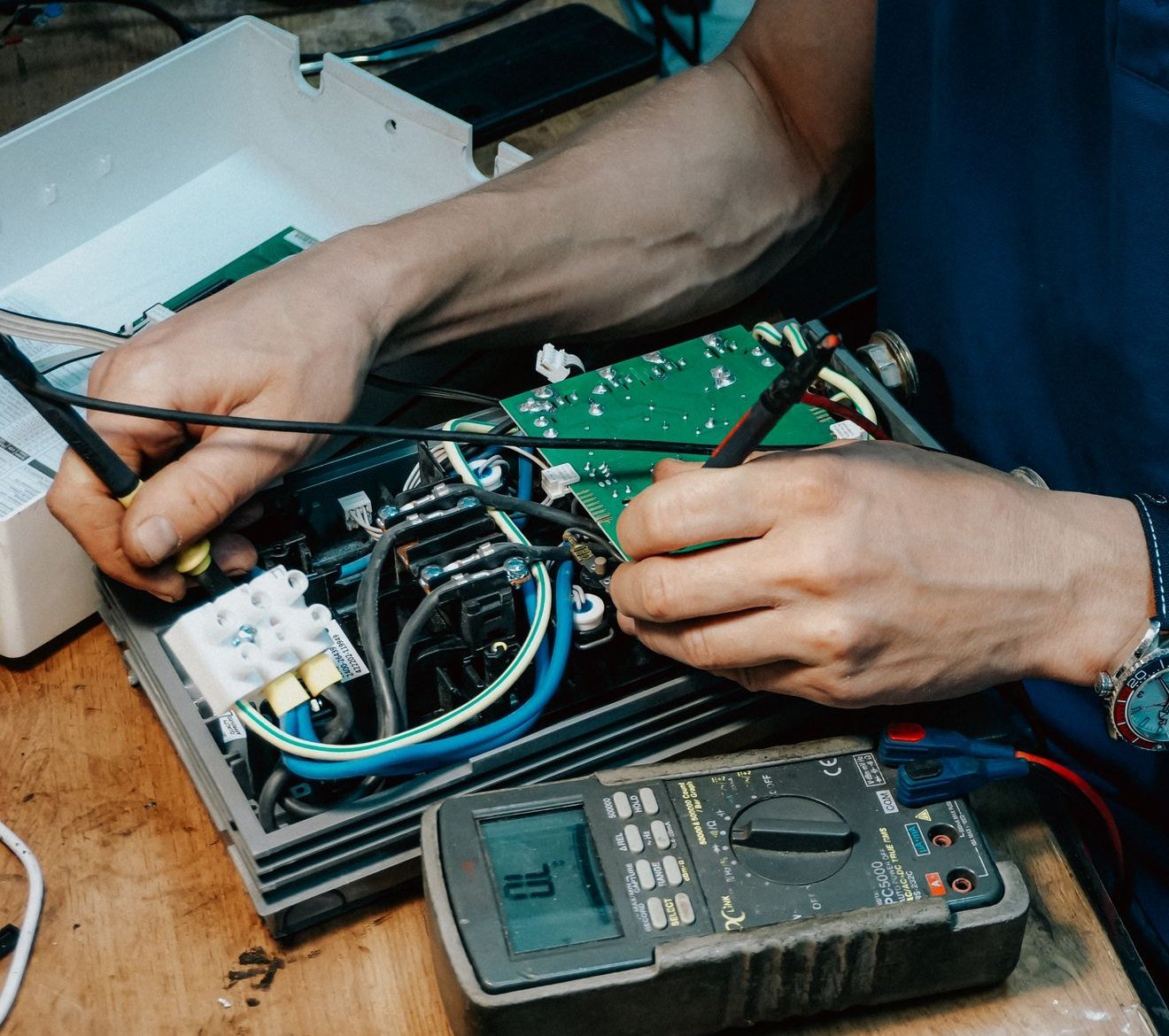 A technician testing a washing machine control board with a multimeter